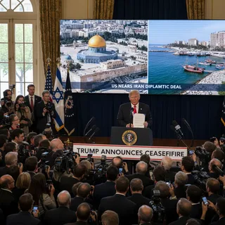 Donald Trump speaking at a podium with a backdrop suggesting a news conference, conveying a political announcement.